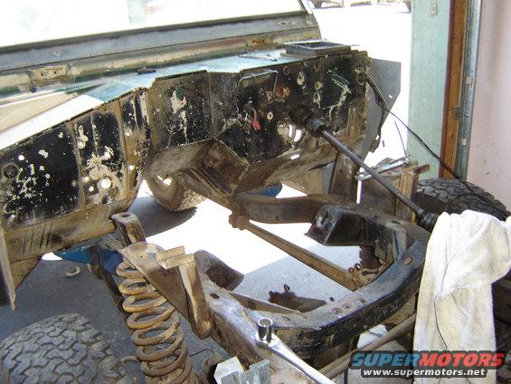 Vehicle frame and suspension components, possibly a Ford Bronco, undergoing repair. Coil springs and chassis parts are visible