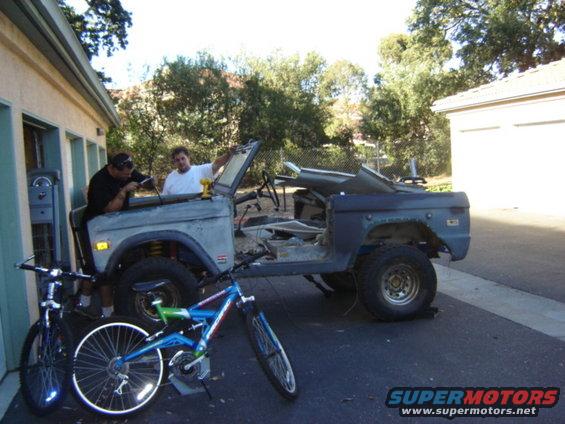 Gray 1971 Ford Bronco with doors removed, undergoing repair, with two bicycles in front