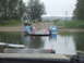 1990 Ford Bronco - A ferry transports vehicles and people across a river on a cloudy day.