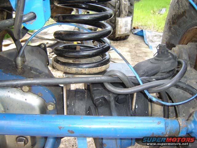 Close-up of vehicle suspension with blue painted parts, black coil springs, and brake lines