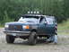 1990 Ford Bronco - A person exits a green 1990 Ford Bronco with off-road modifications.
