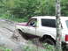 1990 Ford Bronco - Ford Bronco navigating a difficult muddy path in a wooded area.