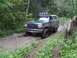 1990 Ford Bronco - This Ford Bronco navigates a muddy path in a forest, with rain visible in the air.