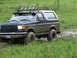 1990 Ford Bronco - This 1990 Ford Bronco is equipped for off-road adventures, seen here navigating a wet, grassy terrain.