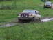 1990 Ford Bronco - A two-tone Ford Bronco navigates a muddy track, with another SUV following in the background.