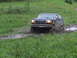 1990 Ford Bronco - A black Ford Bronco navigates a muddy track off-road.