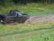 1990 Ford Bronco - A black 1990 Ford Bronco navigates a muddy trail, kicking up water and dirt.
