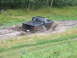 1990 Ford Bronco - Pickup truck navigating a challenging muddy terrain.