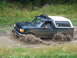 1990 Ford Bronco - A Ford Bronco navigates a muddy trail, splashing water as it goes.
