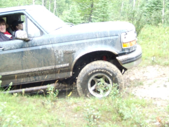 Muddy Ford F-Series truck with people inside, driving off-road