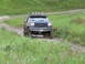 1990 Ford Bronco - A dark green 1987 Ford Bronco navigates a grassy, off-road trail with four lights mounted on its roof rack.