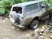 1990 Ford Bronco - Ford Bronco navigating a rocky stream bed surrounded by dense foliage.