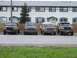 1990 Ford Bronco - Several SUVs are parked in front of a row of townhouses on a cloudy day.