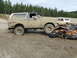 1990 Ford Bronco - A muddy 1990 Ford Bronco is parked on a gravel lot, with another SUV visible in the background.