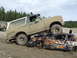 1990 Ford Bronco - A lifted Ford Bronco is driven over a heavily damaged car, with another vehicle visible in the distance.