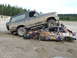 1990 Ford Bronco - A 1990 Ford Bronco is parked on top of a destroyed car in a dirt lot.