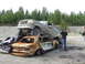 1990 Ford Bronco - A Ford Bronco is parked on top of two heavily damaged cars in a junkyard setting.