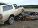 1990 Ford Bronco - A white and maroon Ford Bronco is parked on top of a heavily damaged and rusted car in a junkyard.