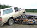 1990 Ford Bronco - A tan and maroon 1990 Ford Bronco is parked on top of a heavily damaged and rusted car.