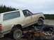 1990 Ford Bronco - A 1990 Ford Bronco is piled on top of a heavily damaged car in a junkyard.