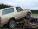1990 Ford Bronco - A dog sits in the driver's seat of a dirty Ford Bronco perched precariously atop a heavily damaged car.