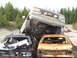 1990 Ford Bronco - A tan Ford truck is precariously perched atop two heavily damaged cars in a junkyard.