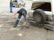 1990 Ford Bronco - A man digs mud from around a stuck Ford Bronco while another person watches.