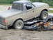 1990 Ford Bronco - A tan 1990 Ford Bronco is positioned on top of a heavily damaged and rusted car.