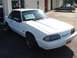 1991 Ford Mustang - A white 1991 Ford Mustang is shown from a three-quarter front view, parked in front of a commercial building.