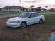 1994 Ford Taurus - A white 1994 Ford Taurus sedan is parked on a grassy area in front of a suburban house.