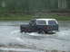 1990 Ford Bronco - A dark green and white 1990 Ford Bronco navigates through a shallow river.