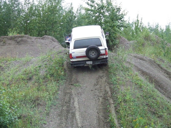 White 1990 Ford Bronco rear view descending dirt hill