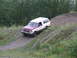 1990 Ford Bronco - This two-tone Ford Bronco navigates a challenging off-road terrain with dense trees in the background.