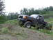 1990 Ford Bronco - A black 1990 Ford Bronco navigates a steep dirt incline with a body of water in the background.
