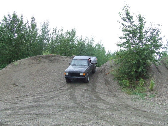 Black 1990 Ford Bronco driving up a gravel hill