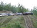 1990 Ford Bronco - Four Ford SUVs and trucks are parked on a dirt hill with trees in the background.