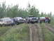1990 Ford Bronco - Several off-road vehicles and their occupants are gathered on a dirt embankment under an overcast sky.
