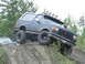 1990 Ford Bronco - This modified Ford Bronco is navigating a challenging off-road course, with another vehicle stuck in the mud.