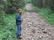 1990 Ford Bronco - Woman with a camera pauses on a rocky path in a dense forest.