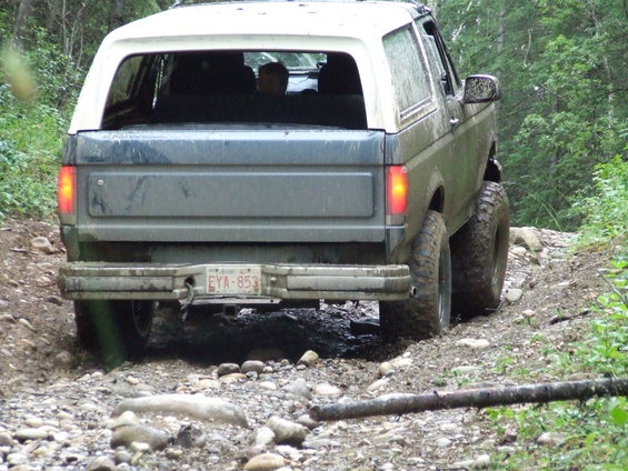 1990 Ford Bronco rear view on a muddy, rocky trail