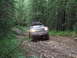 1990 Ford Bronco - A 1990 Ford Bronco navigates a rocky path through a dense forest.