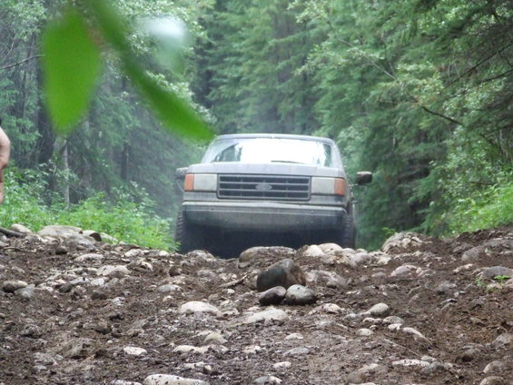 Gray Ford Bronco on a rocky, muddy forest road
