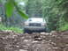 1990 Ford Bronco - A gray Ford Bronco navigates a challenging, rocky path through a dense forest.