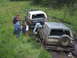 1990 Ford Bronco - Two Ford Broncos are stuck in the mud on a trail with several people observing.
