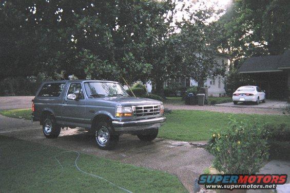 Gray Ford Bronco parked in driveway, white sedan in background