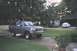 1995 Ford Bronco - A gray Ford Bronco is parked in a driveway next to a house, with a white sedan visible in the background.