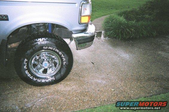 Silver Ford Bronco front fender and tire on wet pavement