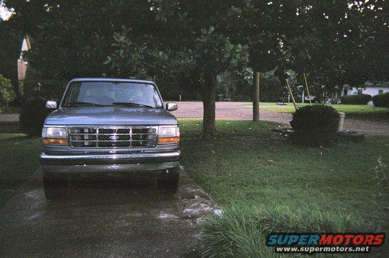 Front view of a blue 1995 Ford Bronco parked in a driveway with trees and grass around
