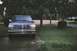 1995 Ford Bronco - This blue Ford Bronco is parked outside on a cloudy day, with trees and a lawn visible in the background.