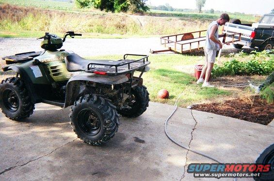 Green ATV parked on concrete, rear view